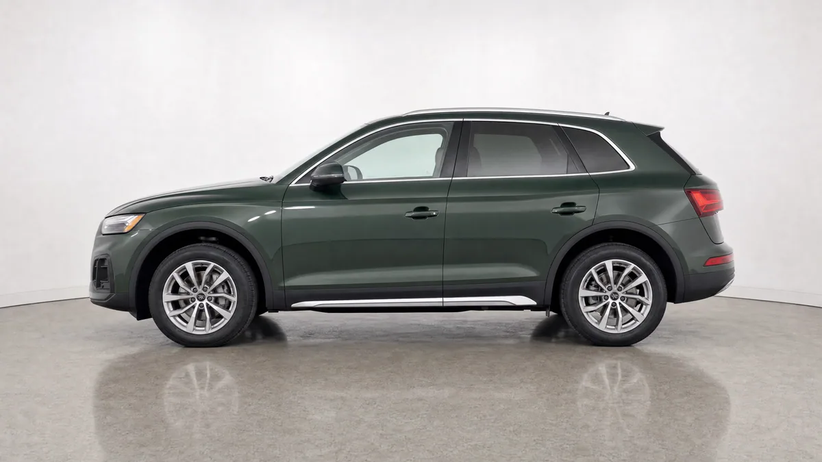 Dark green SUV in a neutral dealer studio, photographed in full driver-side profile