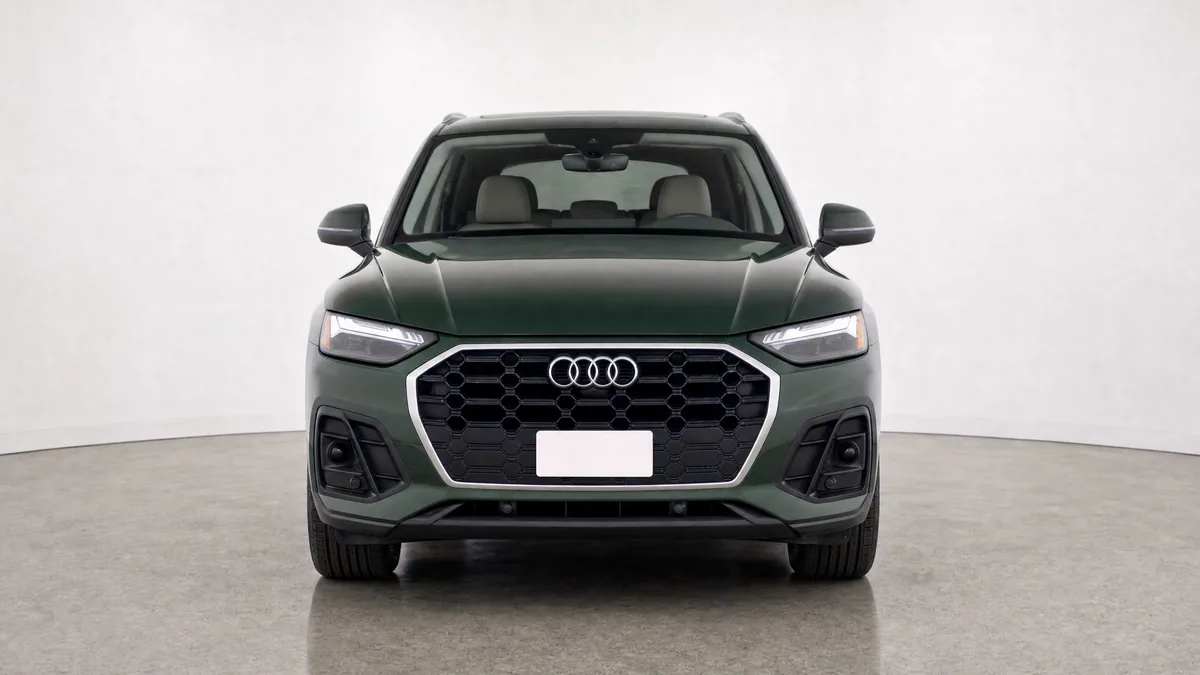 Dark green SUV centred in a neutral dealer studio, photographed straight from the front