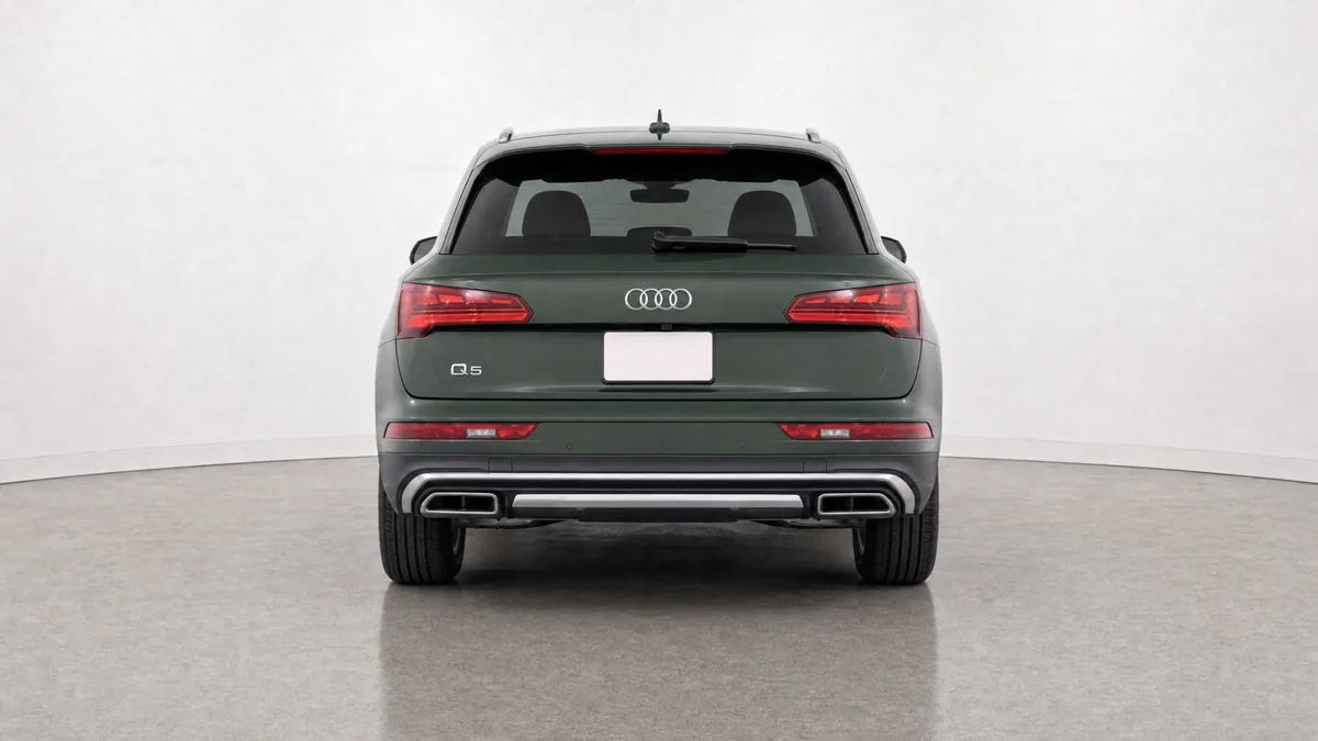 Dark green SUV centred in a neutral dealer studio, photographed straight from the rear