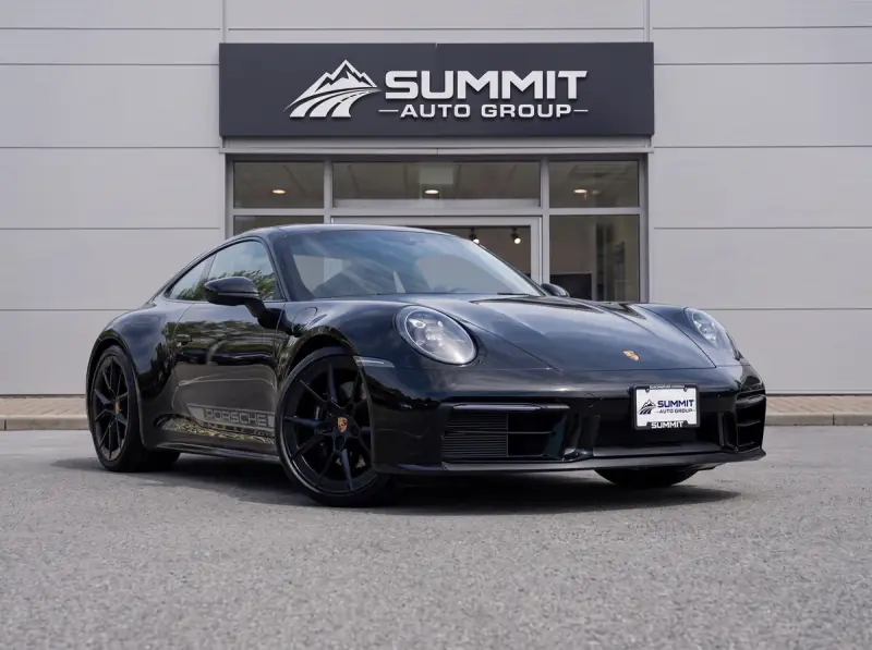 Black Porsche displayed outside a Summit Auto Group dealership with matching branded signage and license plate