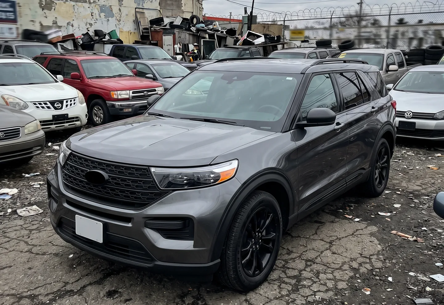 Ford Explorer inventory photo on a cluttered used car lot before CarPixAI background replacement